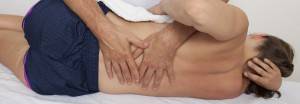Male patient having low back stretched by an osteopath
